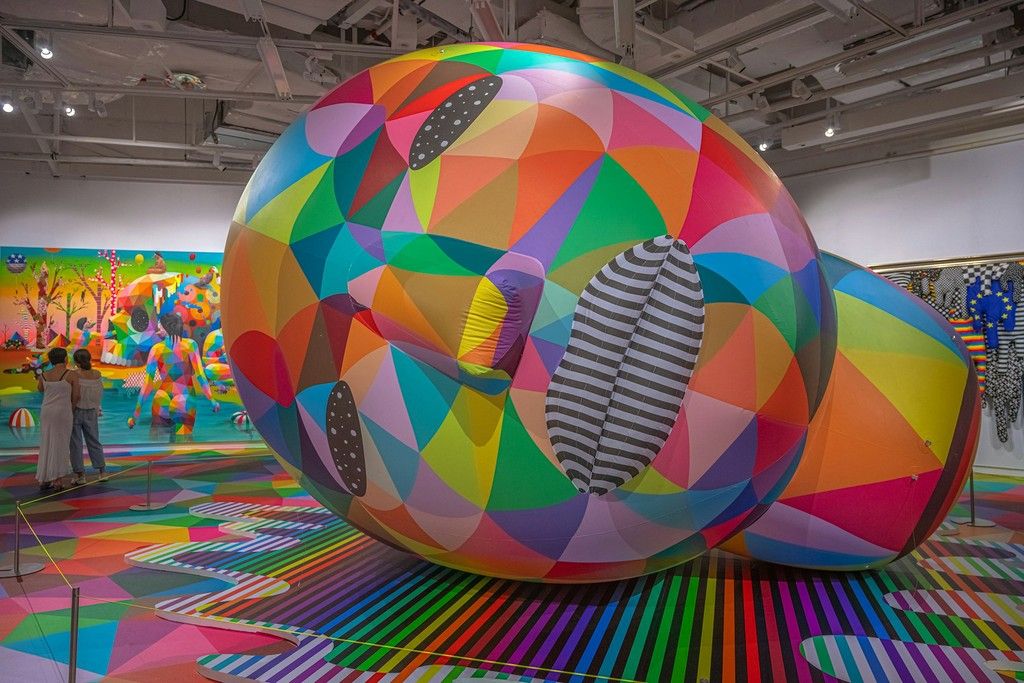 Escultura hinchable gigante cubierta de triángulos de colores en una sala de exposiciones